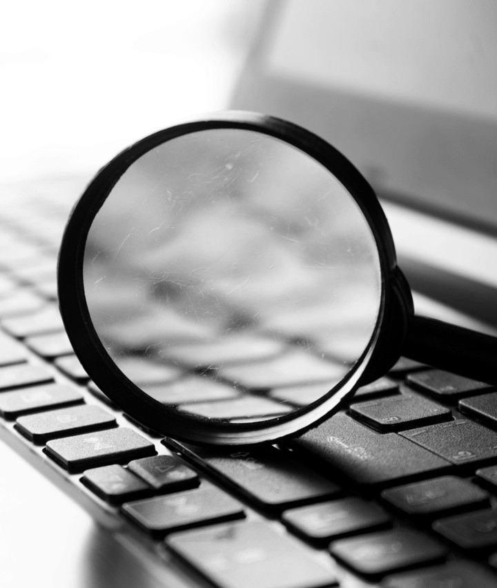 A magnifying glass resting on a laptop keyboard